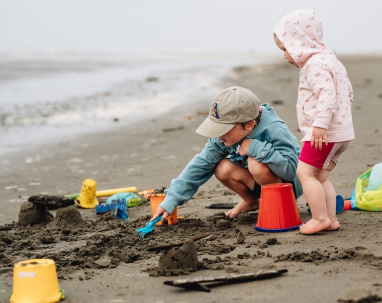 Two children playing with sand toys on a beach.